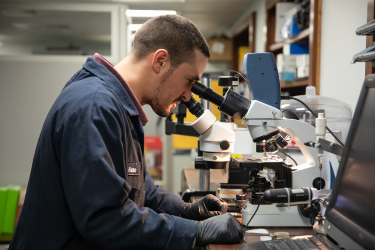 Chemist evaluating sample in microscope