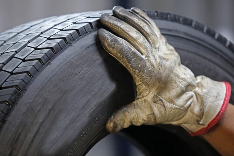 Man inspecting tire tread with glove on